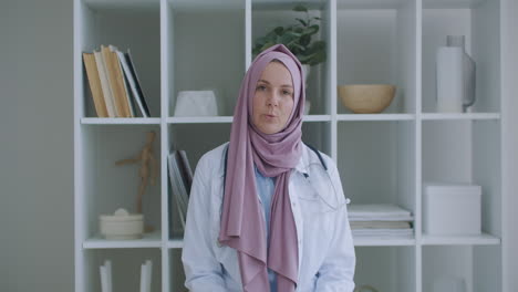 Arabische-Muslimische-Frau-Im-Hijab-Arzt-Per-Videokonferenz.-Porträt-Einer-Muslimischen-Ärztin.-Eine-Medizinische-Fachkraft-Trägt-Einen-Kittel-Und-Einen-Hijab-Und-Sitzt-Auf-Der-Treppe-Eines-Krankenhauses